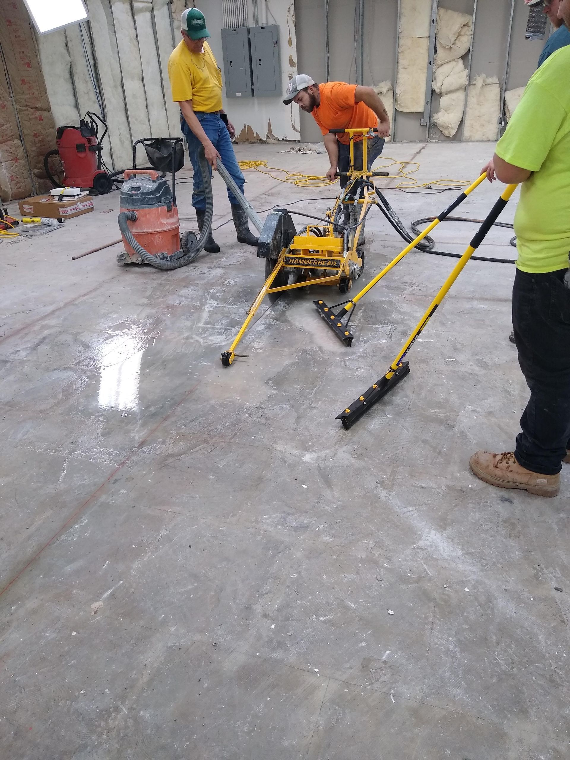 A group of construction workers are working on a concrete floor.
