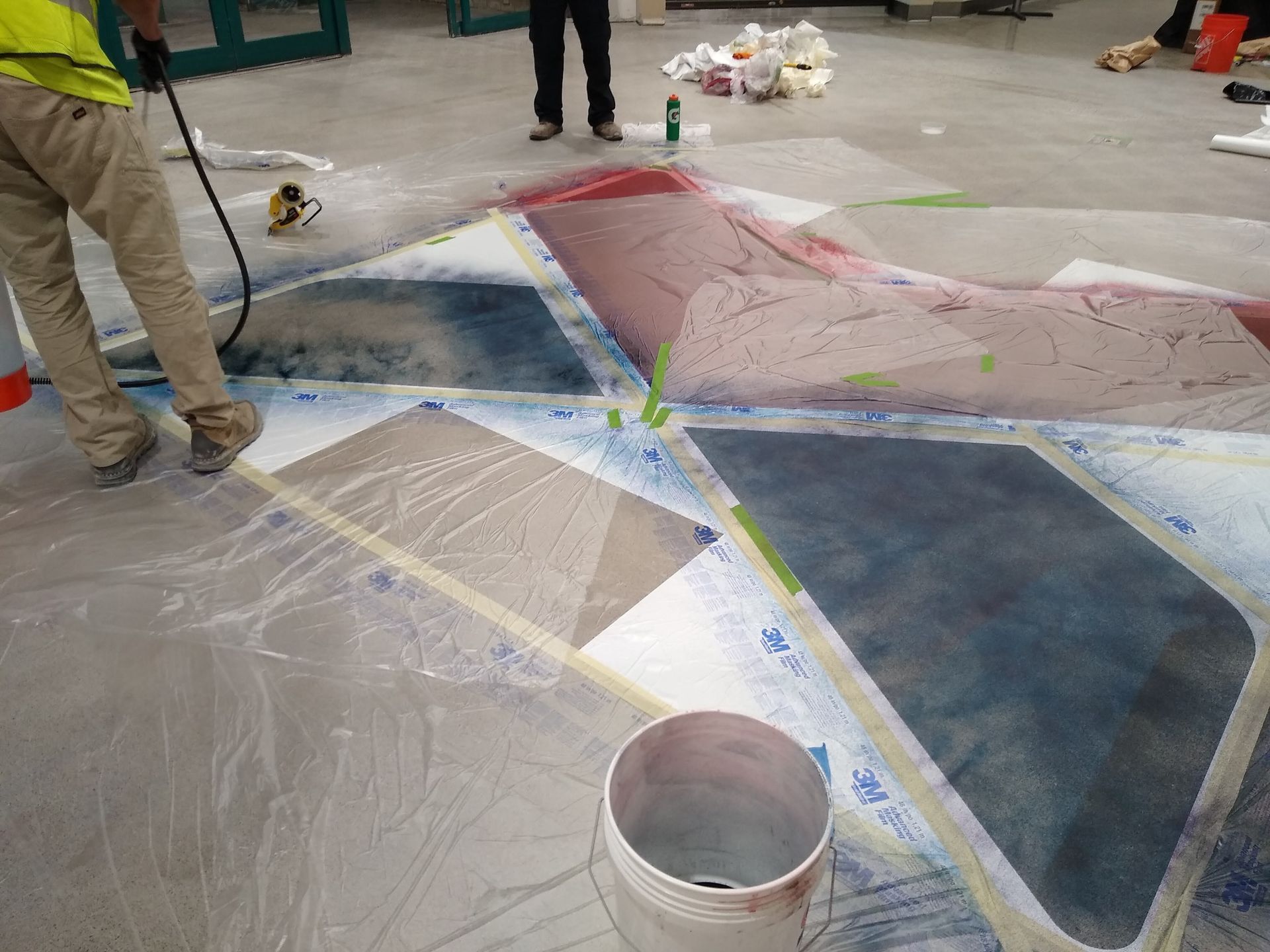 A man is painting a geometric pattern on the floor.