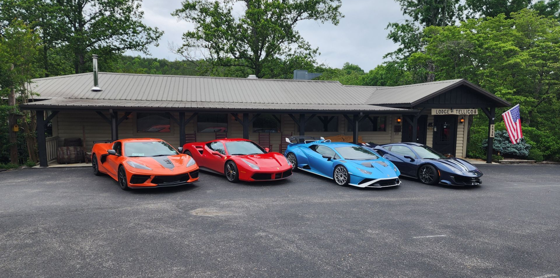 Five sports cars parked outside a building with an American flag.