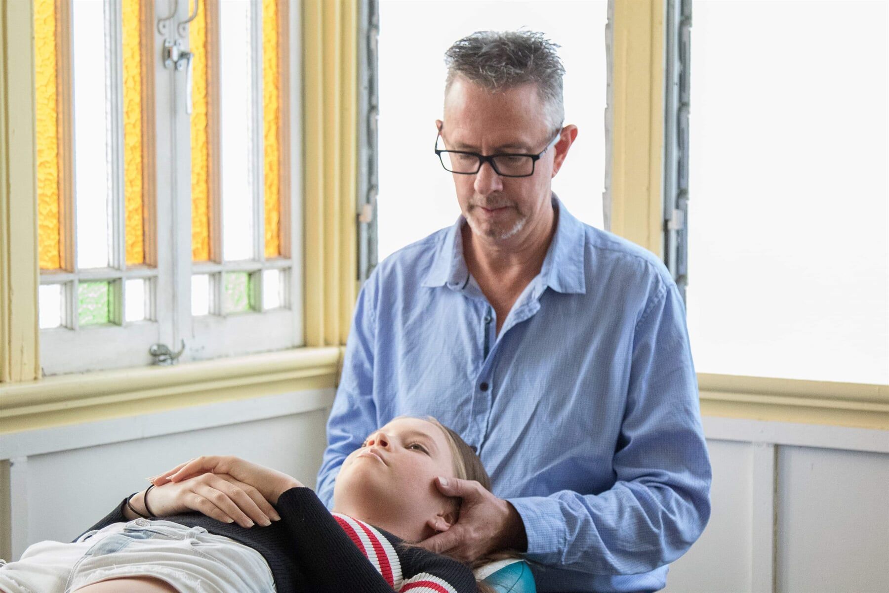 A Man Is Giving A Head Massage To A Child — Trinity Family Chiropractic In Cairns, QLD