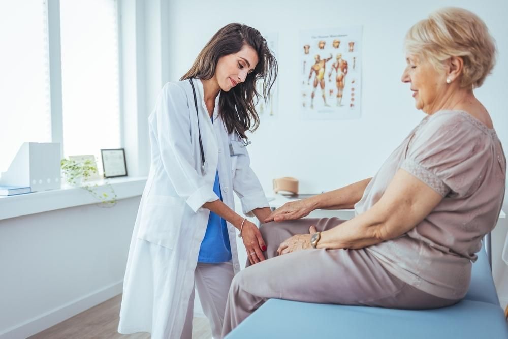 A Doctor Is Examining An Elderly Woman's Leg In A Hospital — Trinity Family Chiropractic In Cairns City, QLD 