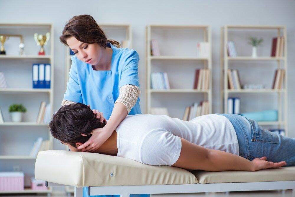 A Woman Is Giving A Man A Massage On A Table — Trinity Family Chiropractic In Cairns, QLD