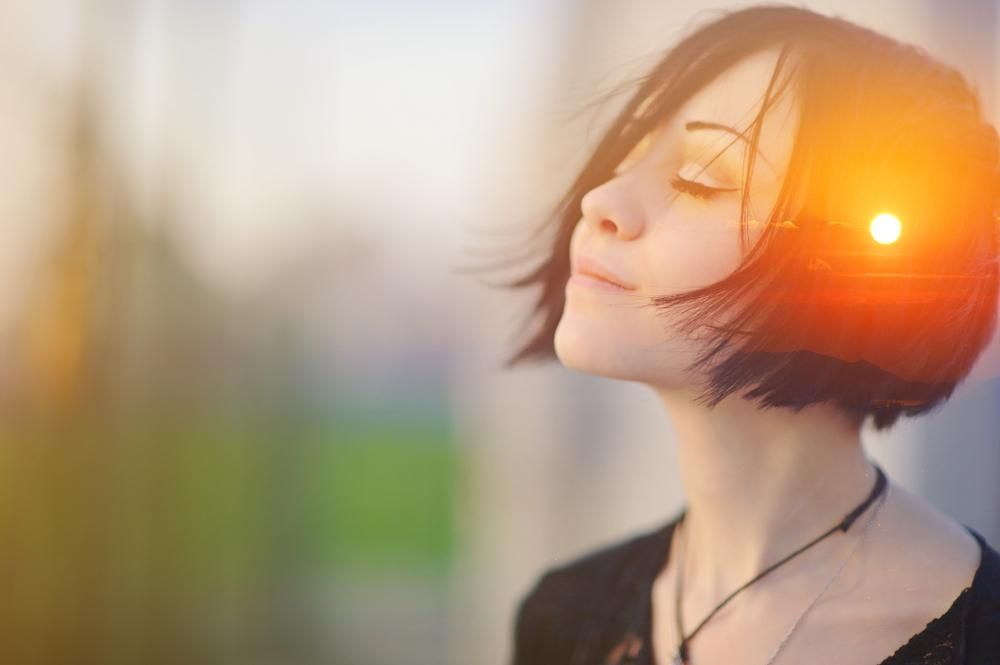 A Woman With Her Eyes Closed And The Sun Shining Through Her Hair — Trinity Family Chiropractic In Cairns, QLD
