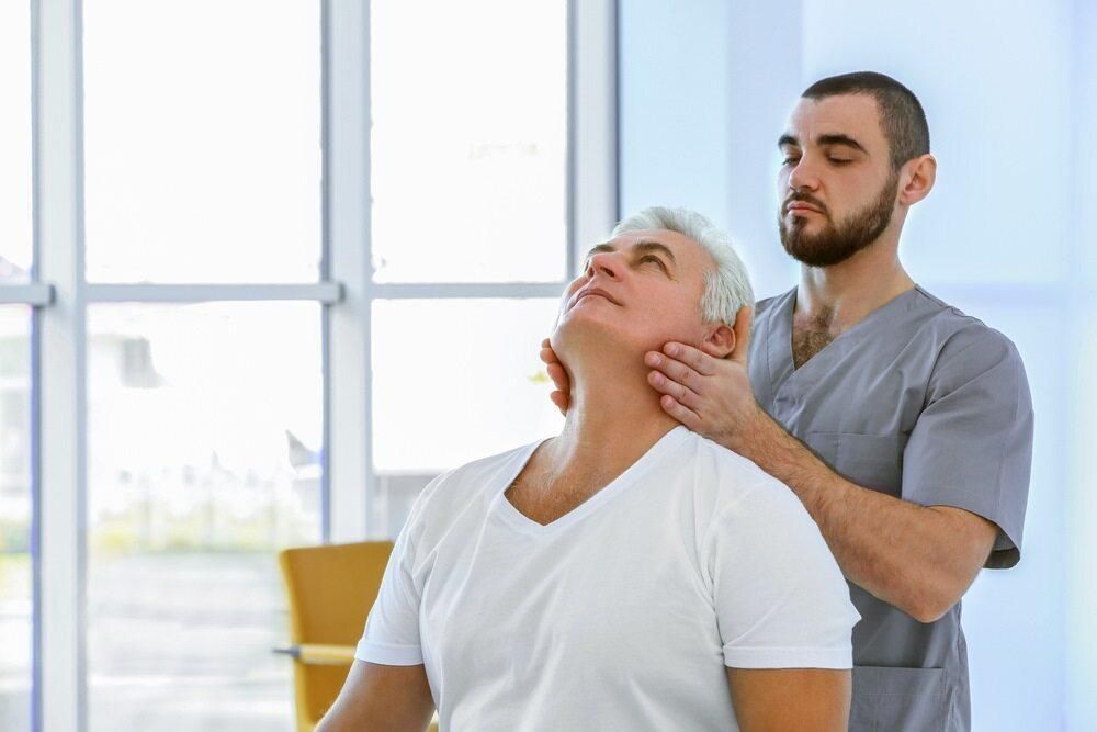 A Man Is Getting A Massage From A Nurse In A Hospital — Trinity Family Chiropractic In North Cairns, QLD