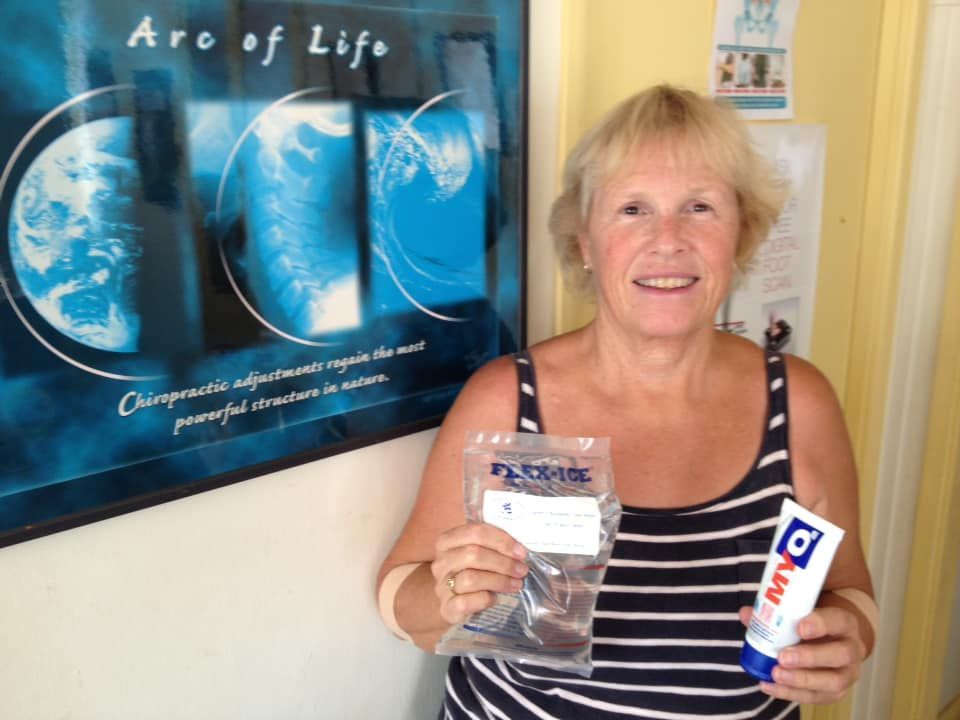 A Woman Is Holding A Tube Of Aqua Toothpaste — Trinity Family Chiropractic In Cairns, QLD