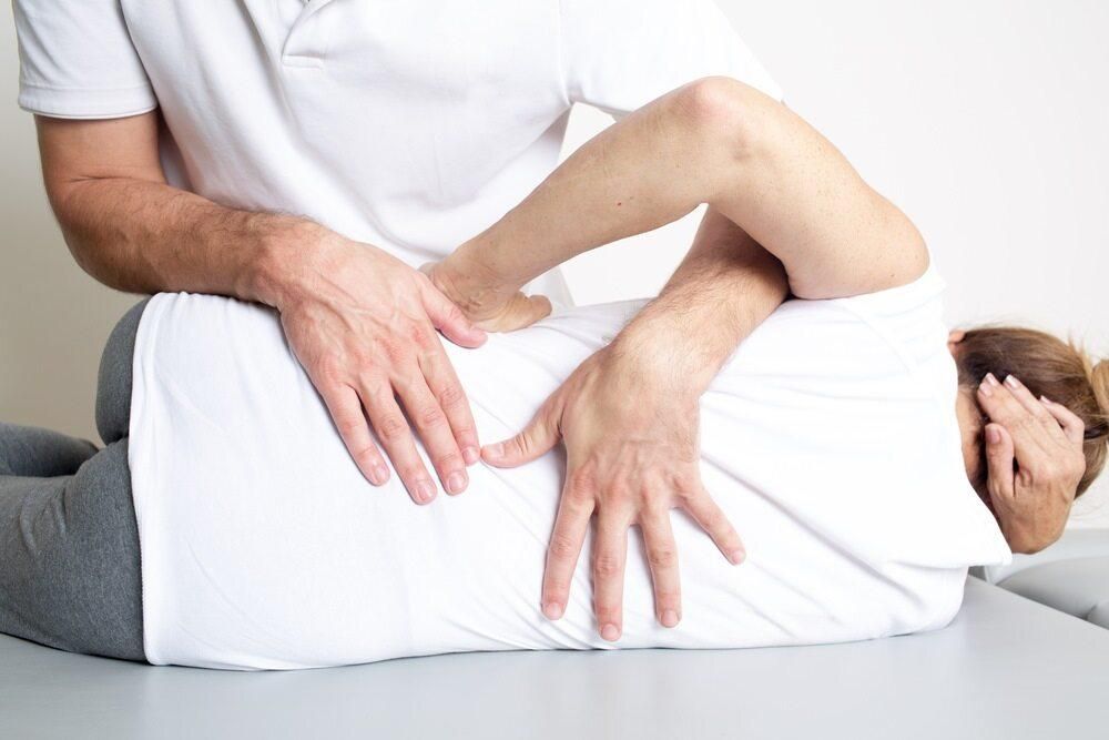 A Man Is Giving A Woman A Massage On Her Back — Trinity Family Chiropractic In Cairns, QLD