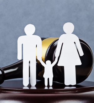 Paper cut outs of a family holding hands next to a judge 's gavel