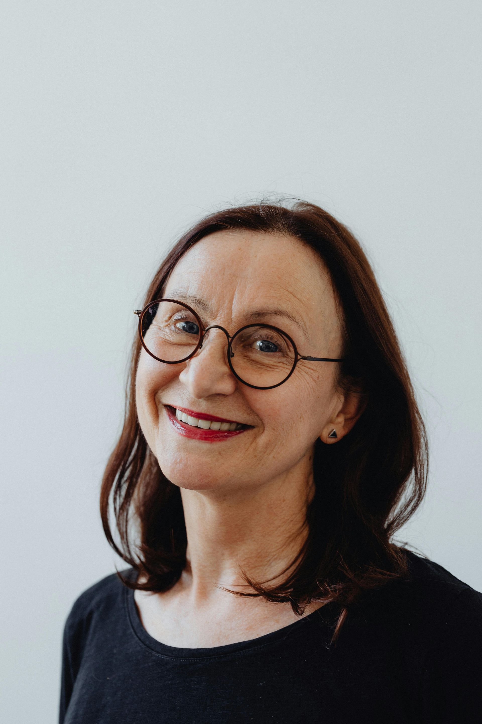 A woman wearing glasses and a black shirt is smiling.