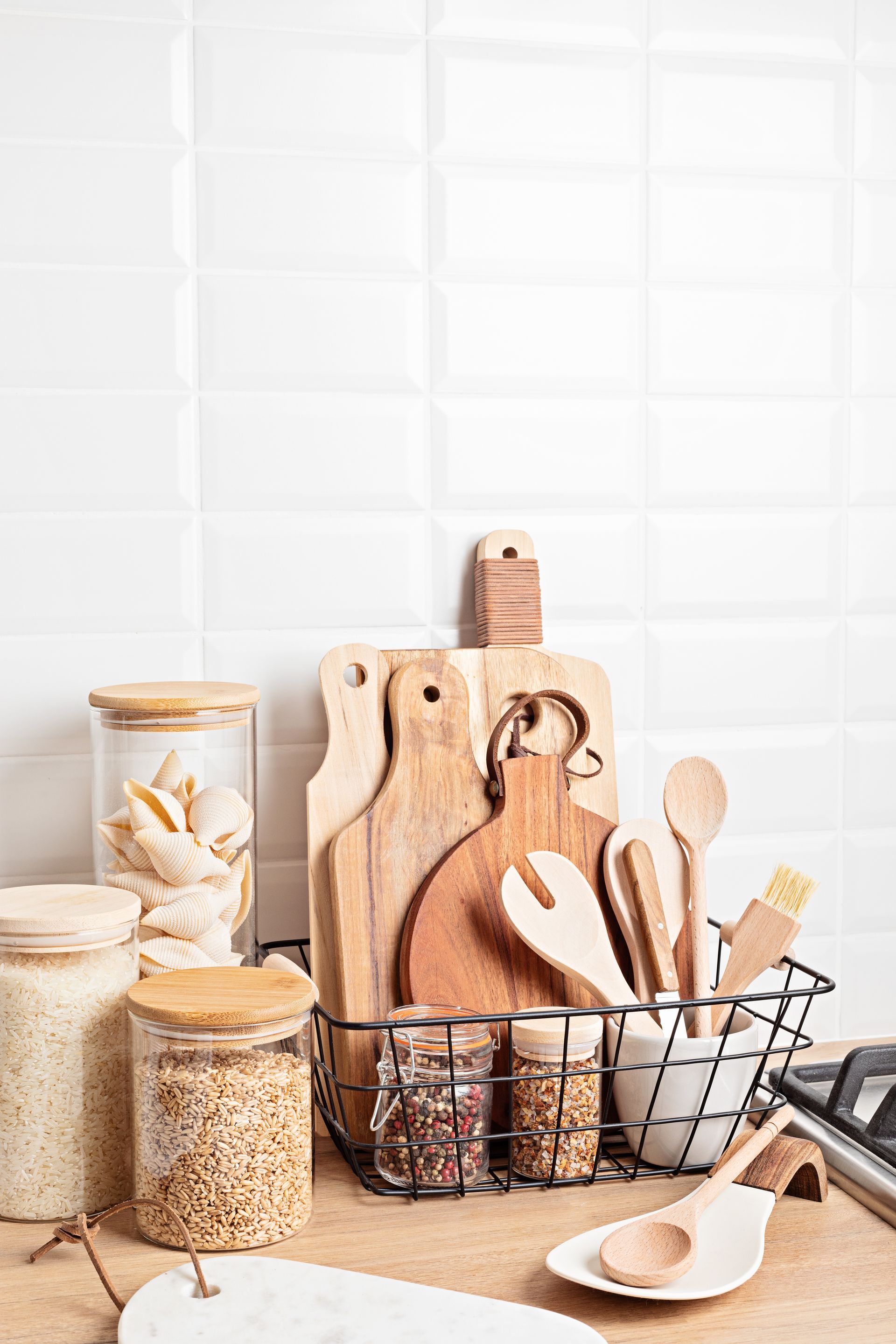 Kitchen utensils and pantry jars arranged on a counter against a white tiled backsplash