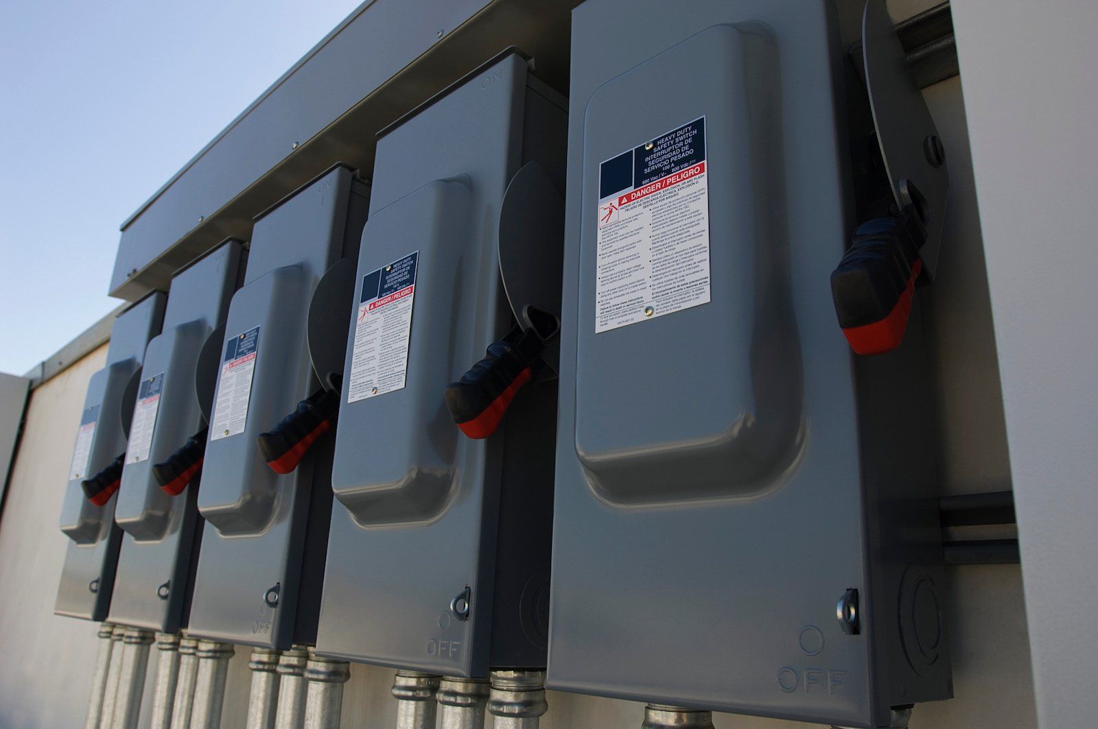 A row of electrical boxes are lined up on the side of a building.