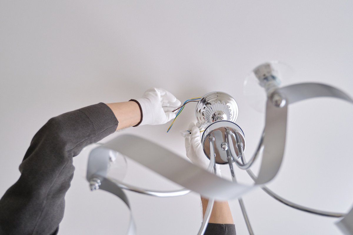 A person is installing a light fixture on the ceiling.
