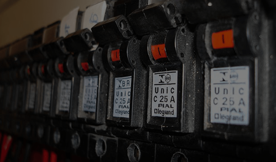 A row of electrical breakers are lined up on a wall.
