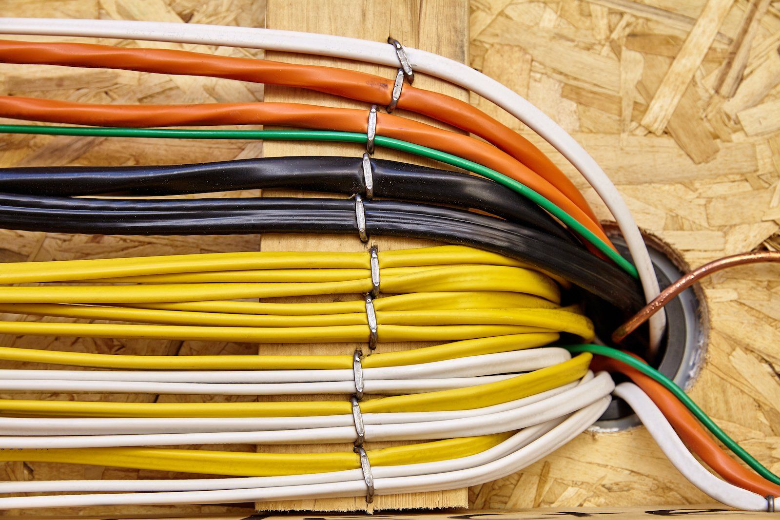 A bunch of wires are coming out of a hole in the wall.