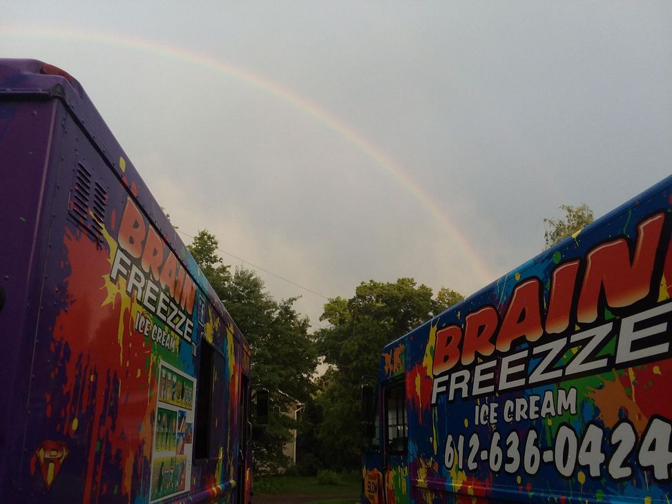 Rainbow over colorful food trucks in a parking lot