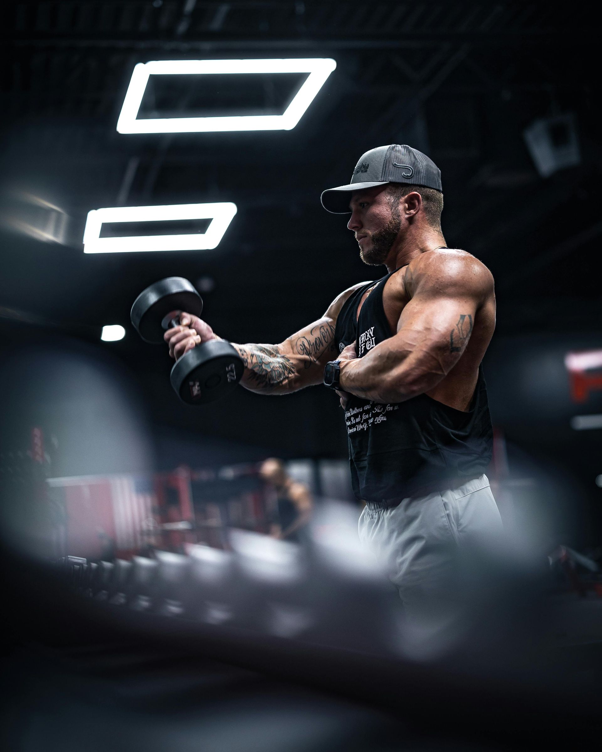 A man is lifting a dumbbell in a gym.
