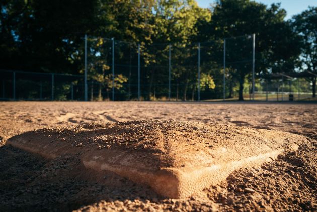 Baseball player sliding into home plate, catcher in front. Blue and gold uniforms, action shot.