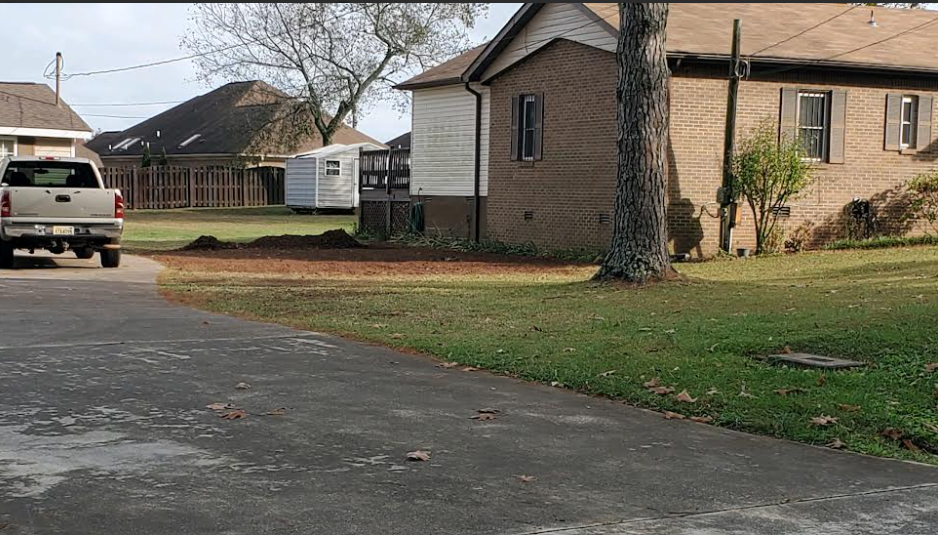 Suburban street with a parked white SUV, brick houses, a large tree, and a grassy yard