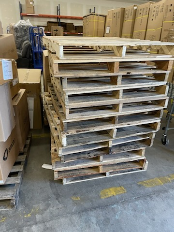 A bunch of wooden pallets are stacked on top of each other in a warehouse.