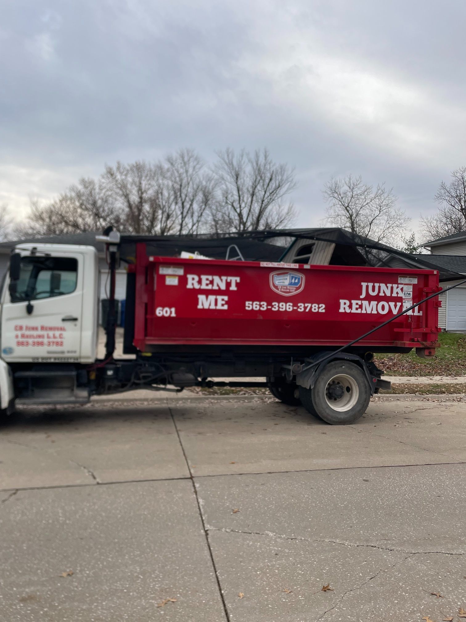 Red "Rent Me Junk Removal" truck with a full container.