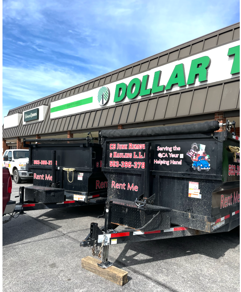 Dumpsters parked in front of a Dollar Tree store; black containers, green and white store sign.