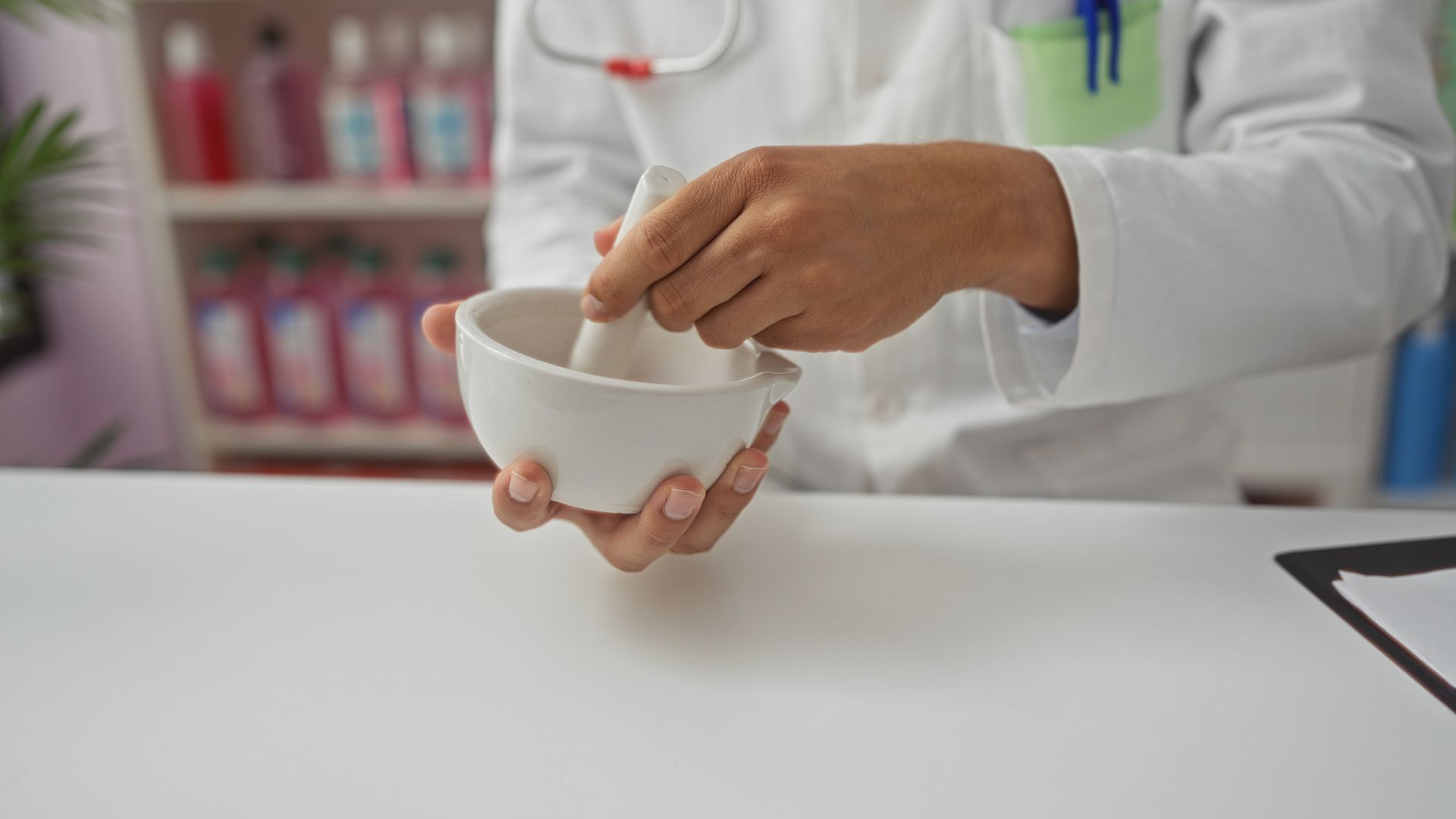 A pharmacist using a mortar and pestle to compound a medication.