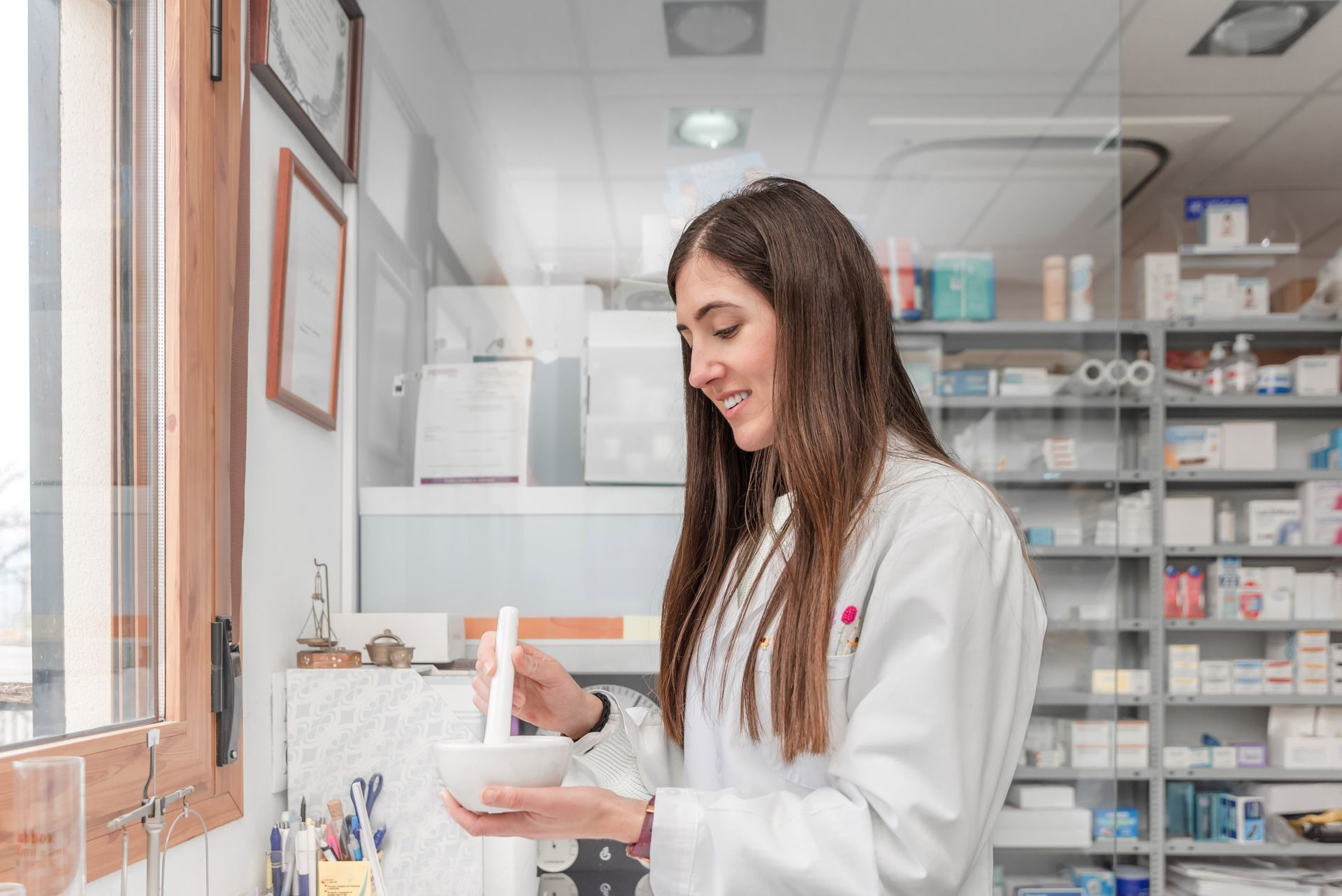 A female pharmacist preparing compound medicine using a mortar and pestle in pharmacy.