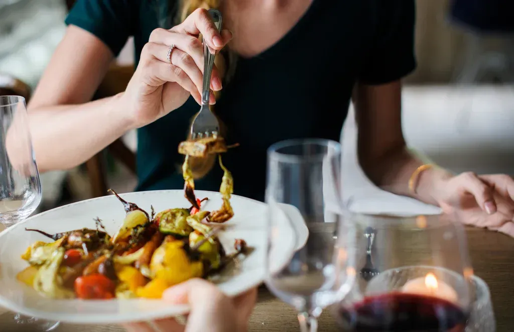 A woman is eating a plate of food with a fork in a restaurant.