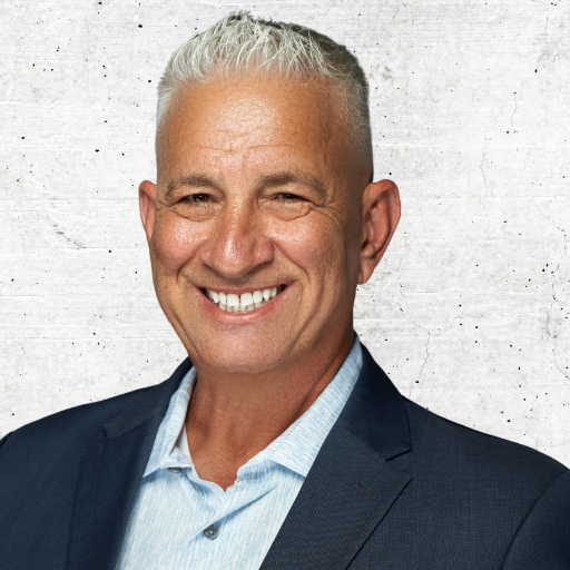 Smiling man in a navy blazer and light blue shirt against a light gray background