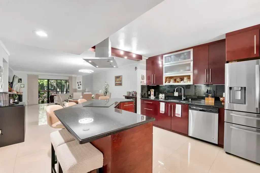 Modern kitchen with red cabinets, stainless steel appliances, and a central island with stools