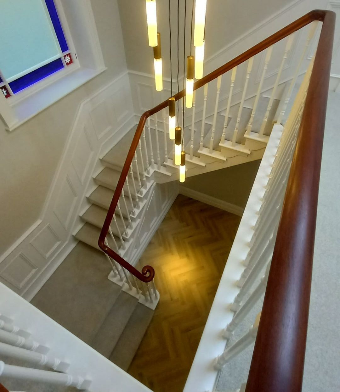 Thoughtfully detailed staircase – warm herringbone floor and ornate balustrade refinished for timeless sophistication