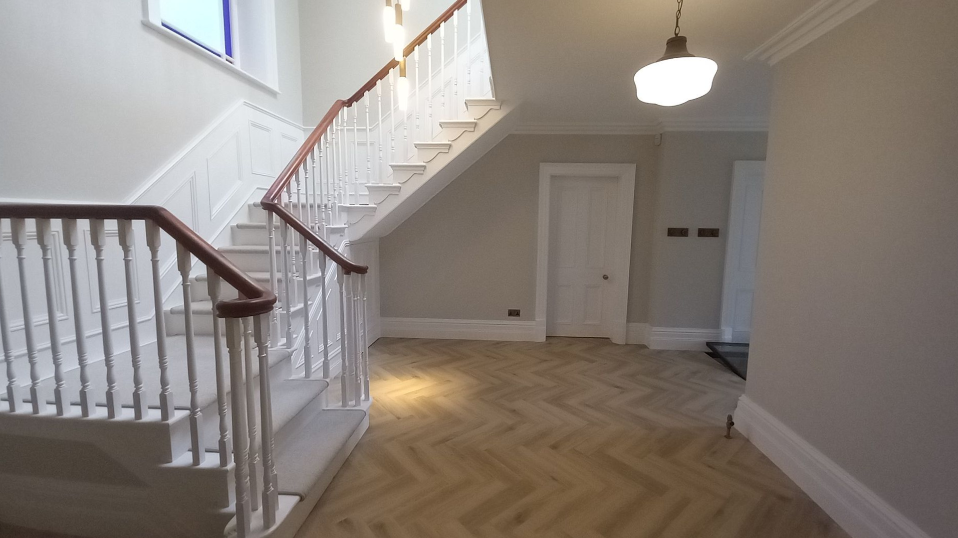 Heritage staircase and landing – deep-toned handrail crowning pristine white spindles, creating a welcoming centrepiece