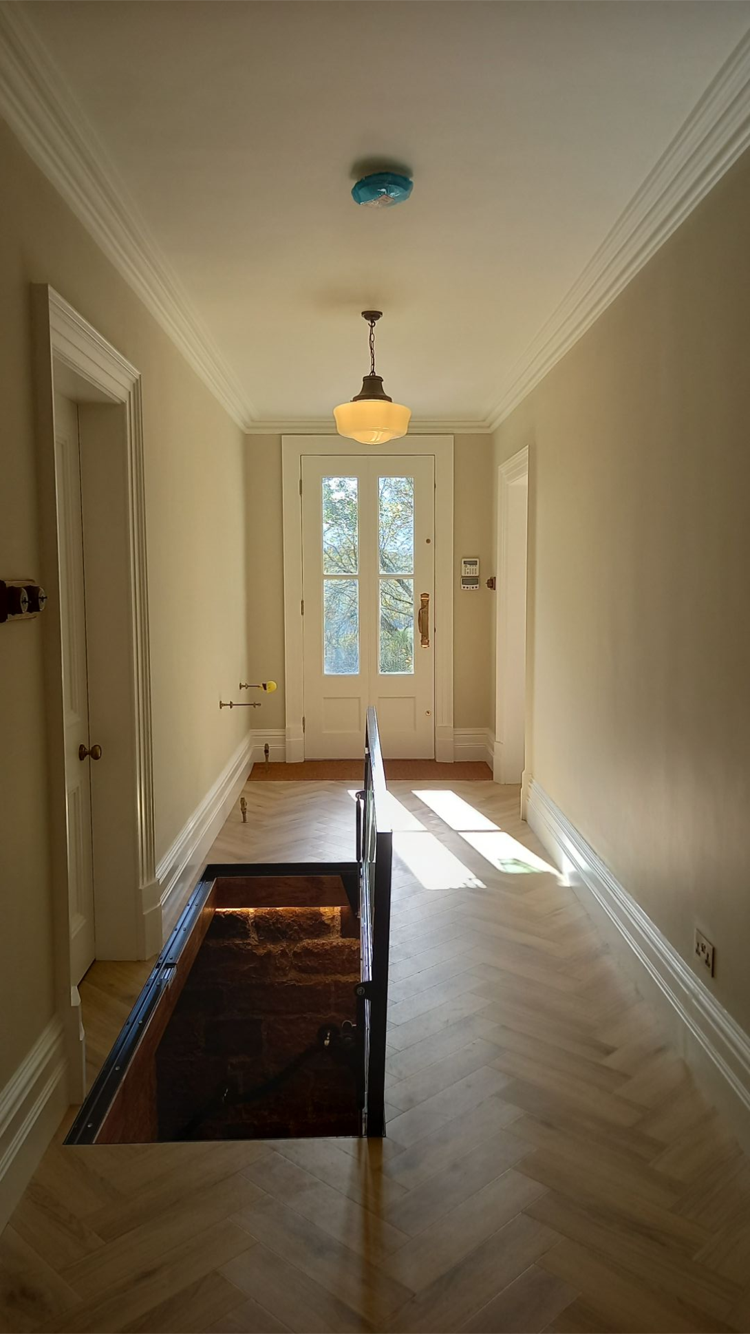 Period hallway leading to front entrance – soft neutral tones and original herringbone flooring preserved with care