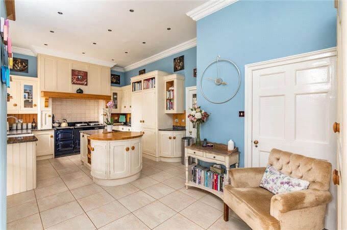 Seamless family kitchen and dining – curved island and polished table coordinated in a warm period home