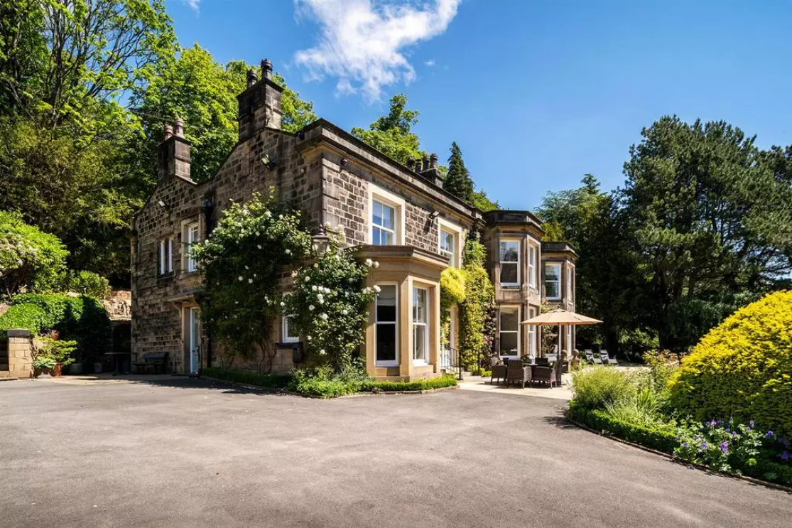 Gracefully restored period stone house exterior, original mullioned windows and ivy-clad walls preserved with thoughtful care