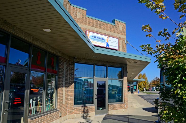 Brick storefront with blue awning and glass windows on a sunny street corner