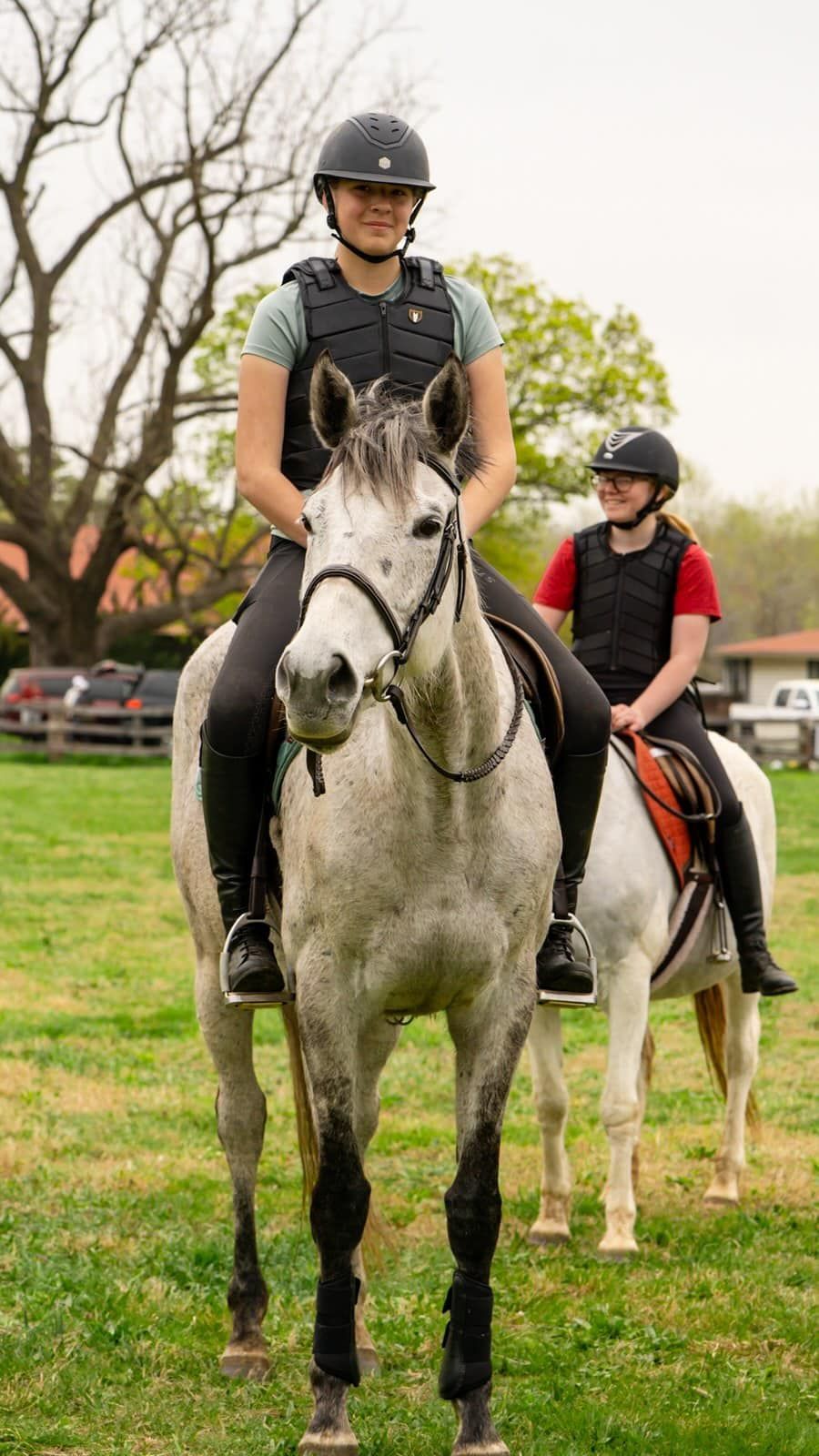 Two people are riding horses in a field.