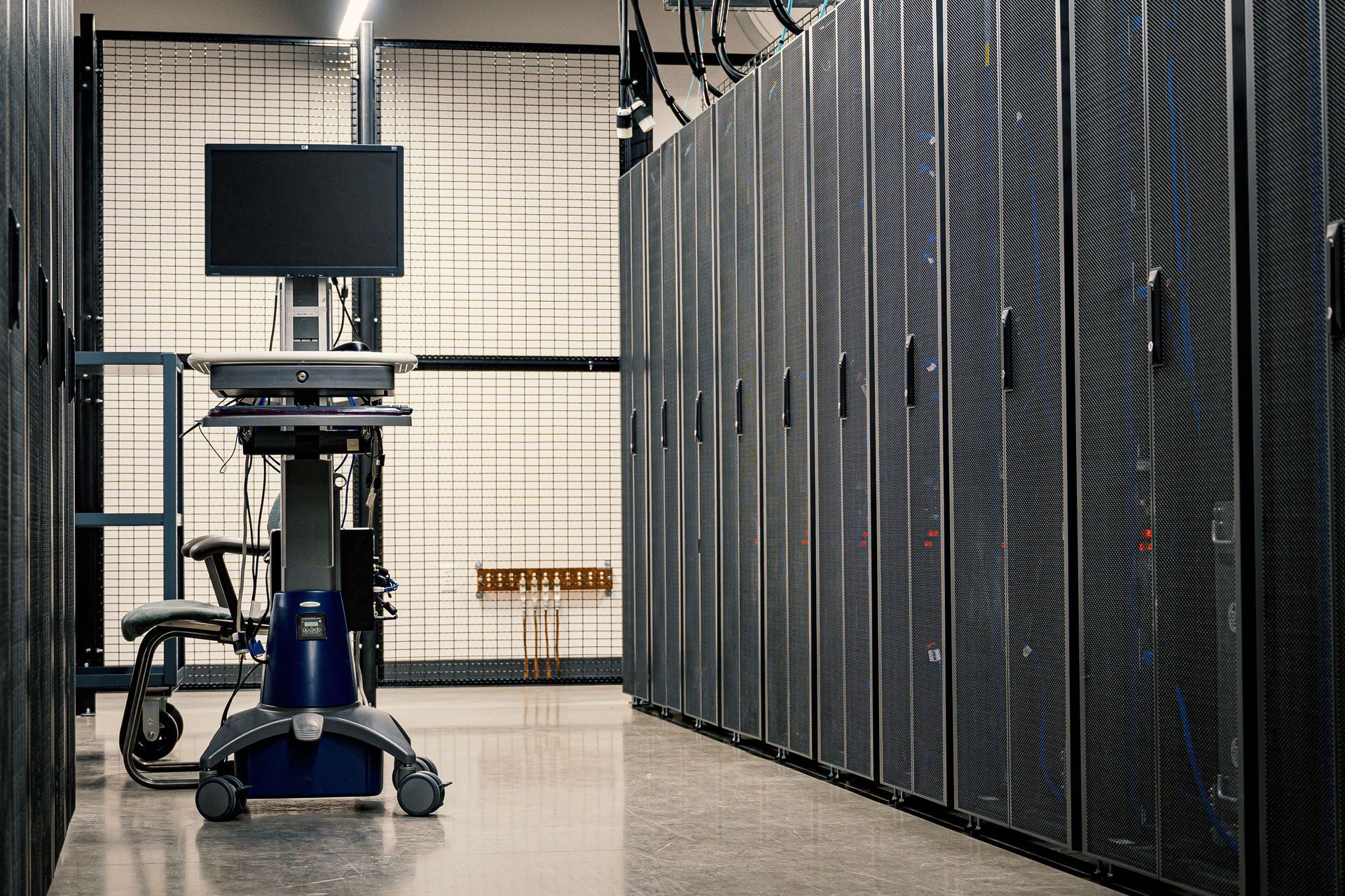 Medical cart with monitor beside tall server racks in a data center hallway