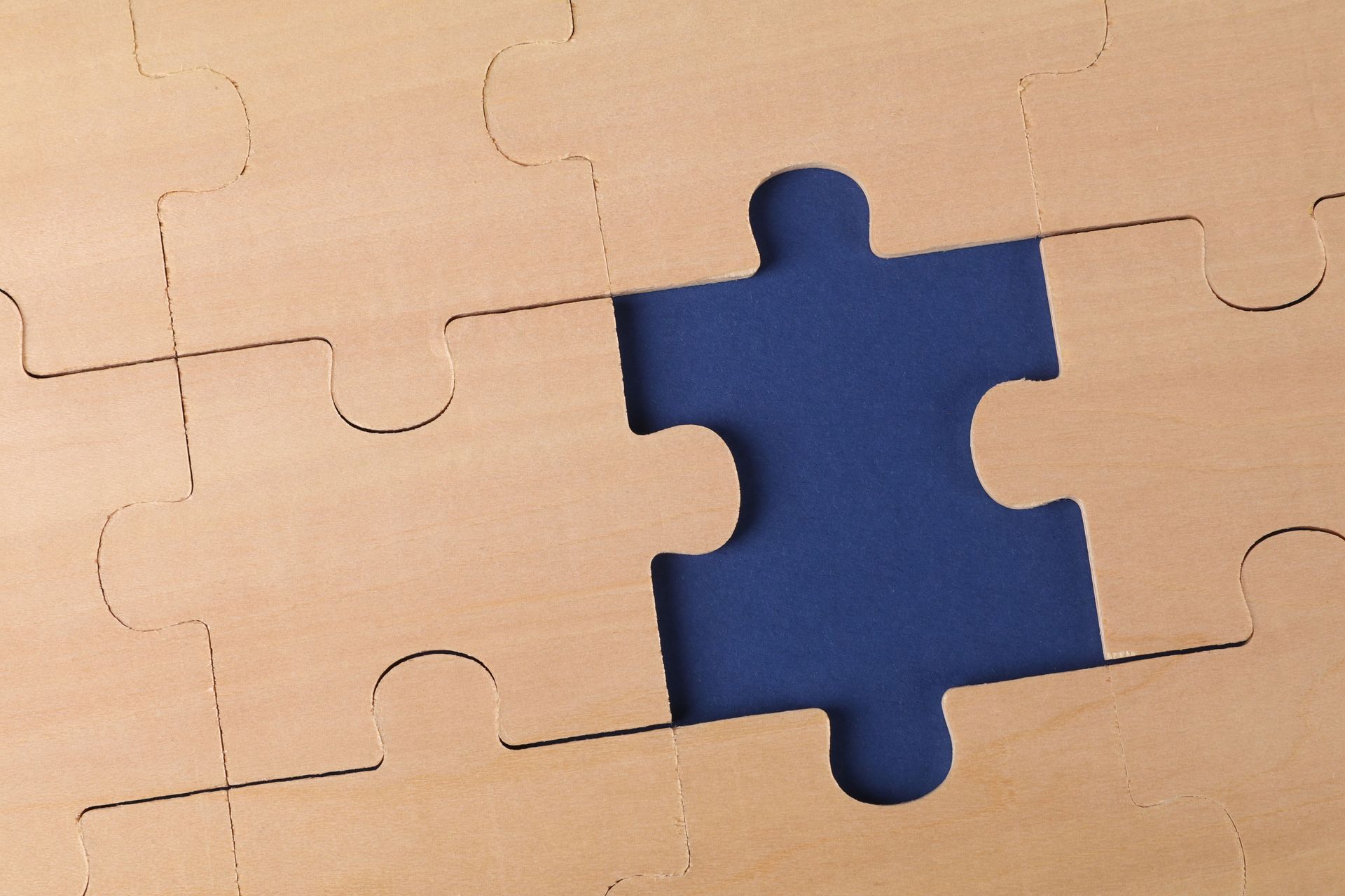Blue puzzle piece missing from a tan jigsaw puzzle background