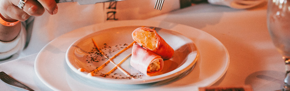 Plato de postre con pequeños pasteles y salsa sobre una mesa blanca en un restaurante.