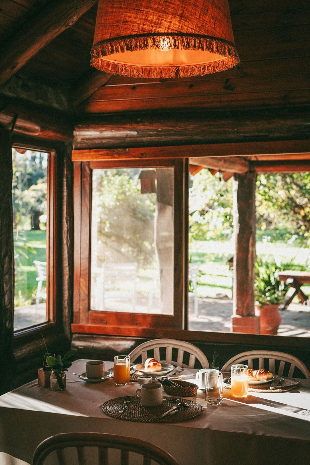 Acogedor comedor de madera con una mesa puesta para el té junto a ventanas soleadas.
