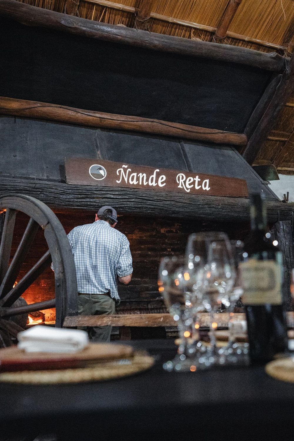 Interior de un restaurante rústico con una persona de pie cerca de un letrero en la pared que dice 
