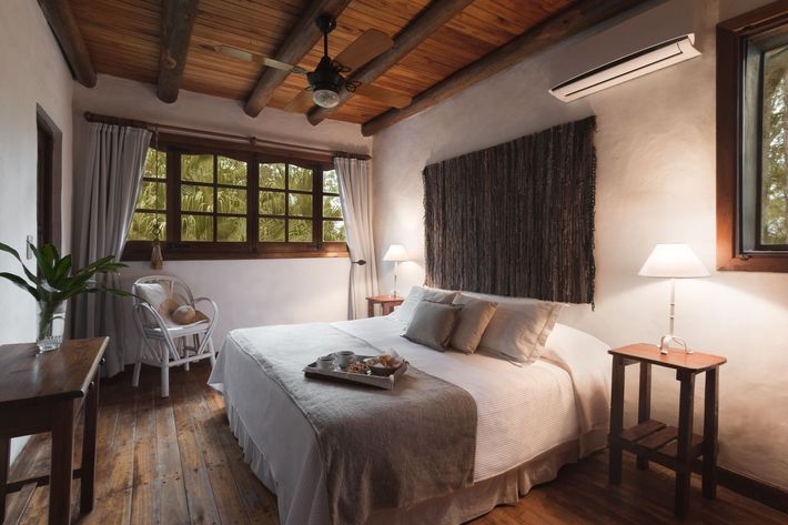 Habitación acogedora con una cama grande, techo de madera y una lámpara junto a la ventana.