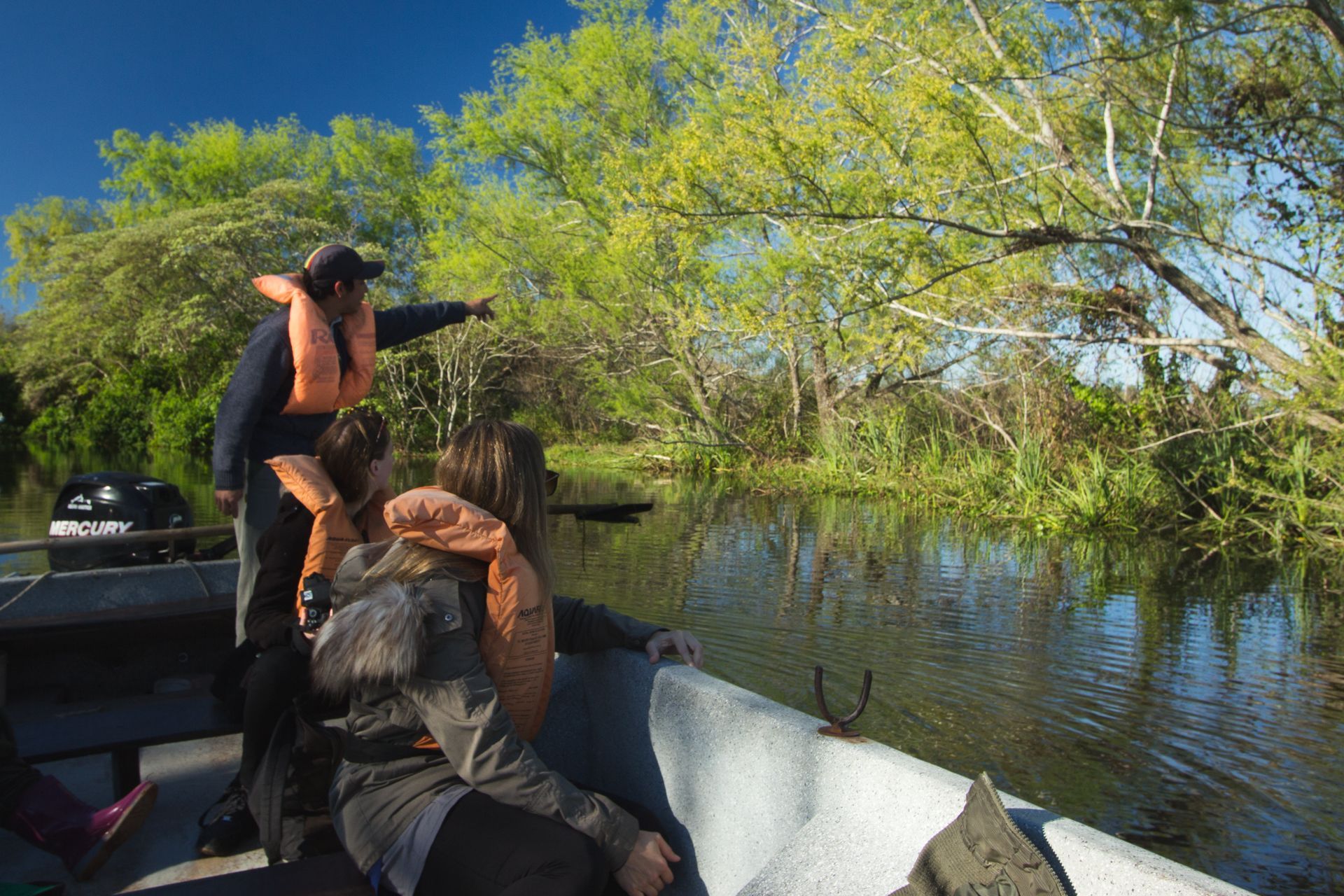 Dos personas en una pequeña barca navegando por un tranquilo río de manglares bajo un cielo azul