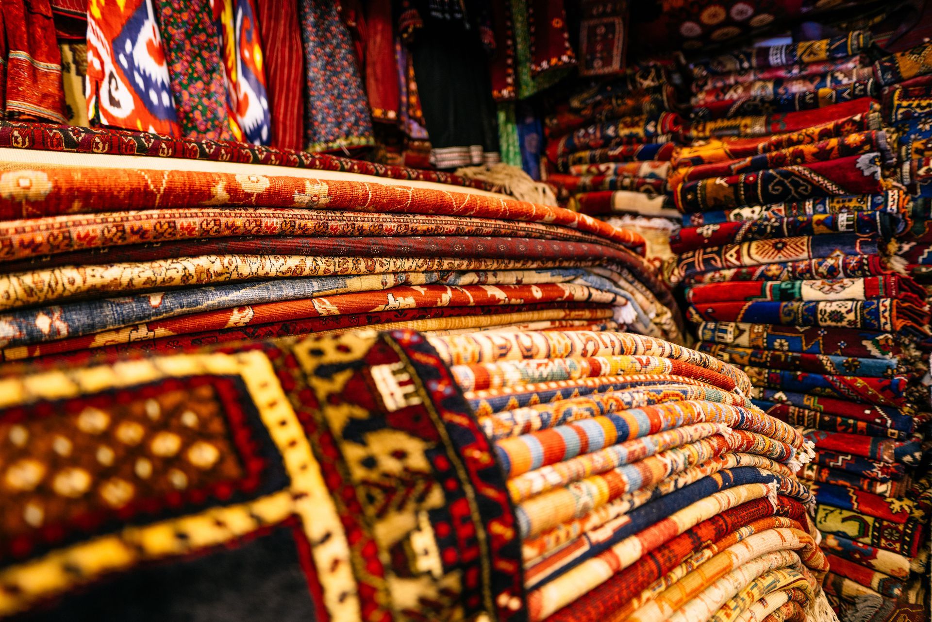 Traditional oriental rugs folded and stacked in a store showcasing intricate craftsmanship.