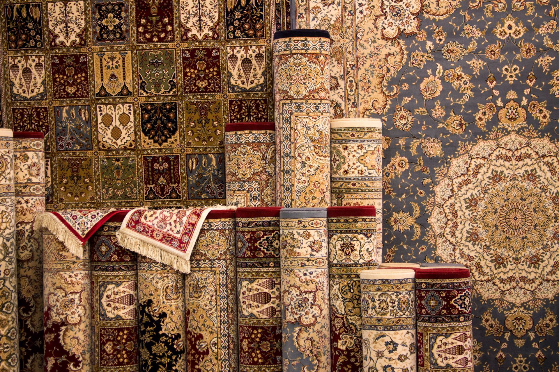 Oriental rug showroom showcasing rolled carpets with detailed motifs and rich textures.