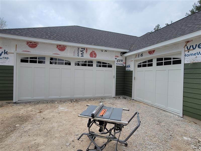 A large gray garage door is sitting in front of a brick house. A large gray garage door is sitting in front of a brick house.