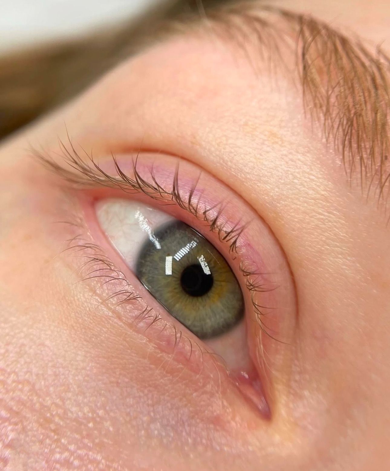 A close up of a woman 's green eye with long eyelashes.