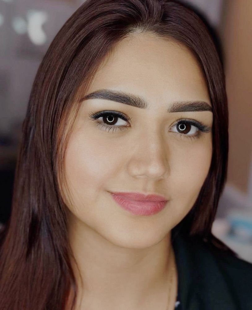 A close up of a woman 's face with long brown hair.