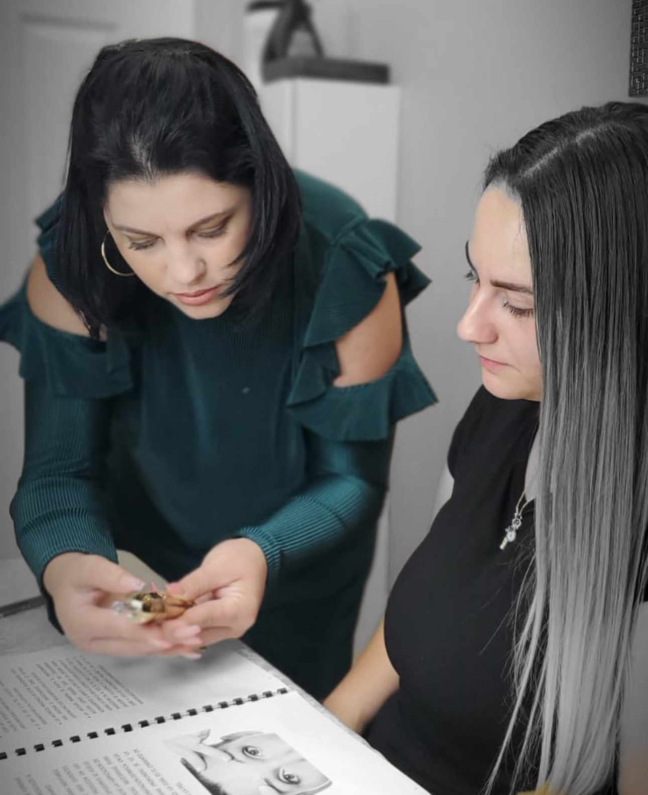 Two women are looking at something in a book