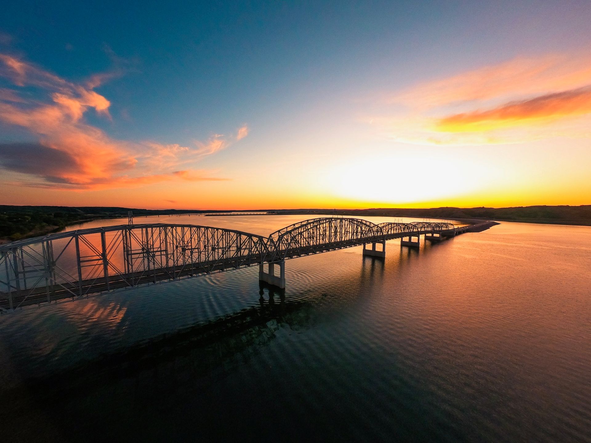 Weathercraft - Chamberlain, South Dakota's Trusted Roofing Contractor An aerial view of a bridge over a body of water at sunset.